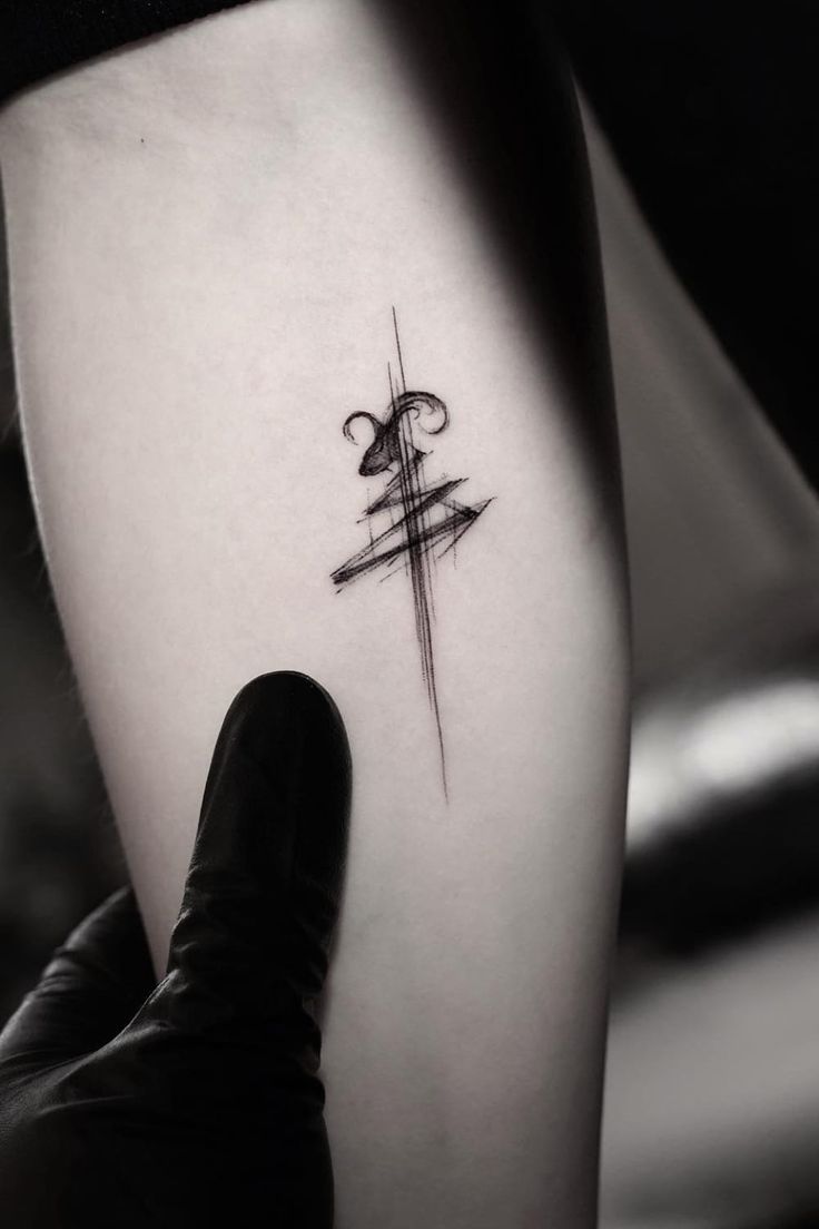 a person with a tattoo on their arm holding up a cross and an arrow in the middle