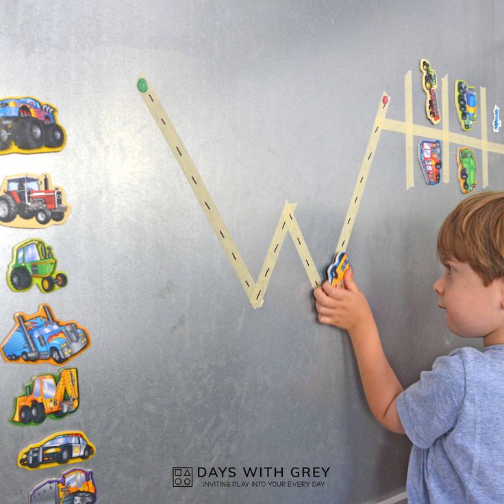 a little boy that is standing in front of a wall with magnets on it