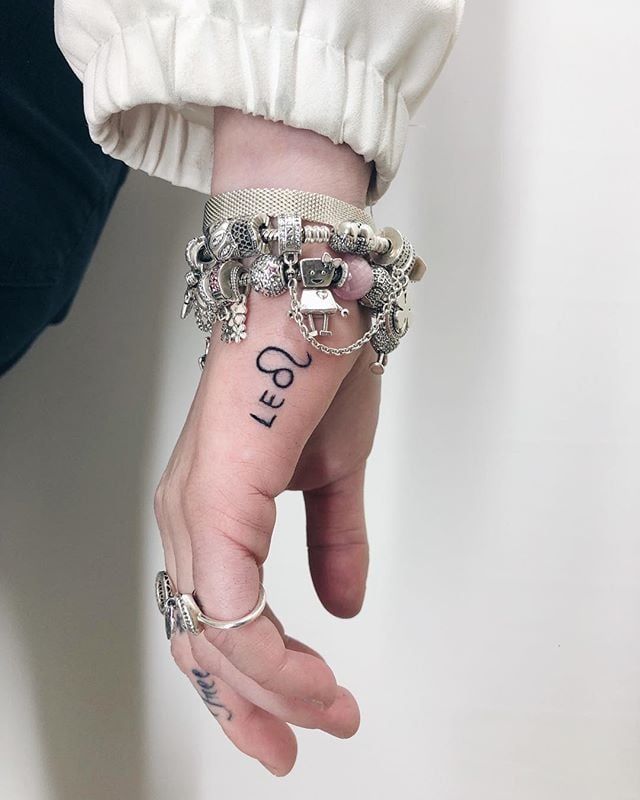 a woman's hand with a wrist tattoo that says god on the middle finger