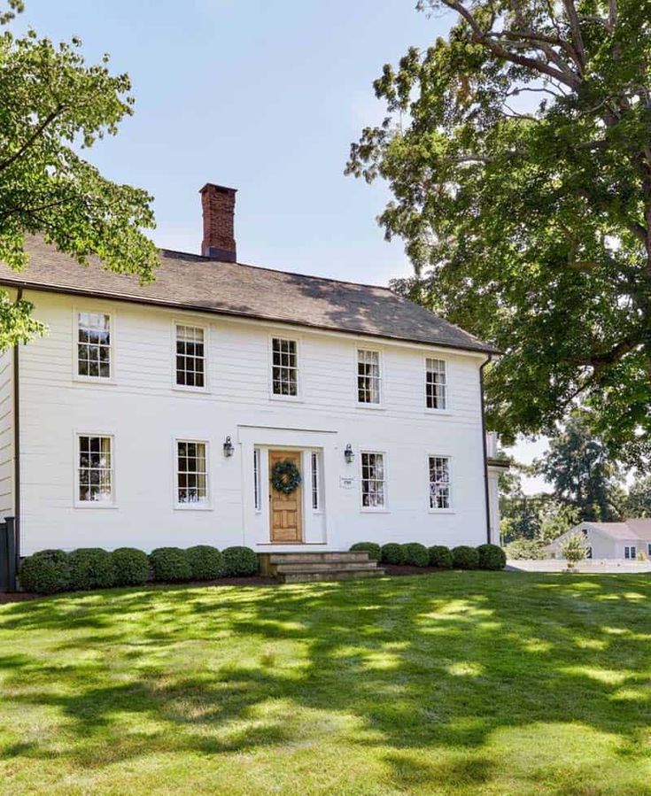 a large white house sitting on top of a lush green field