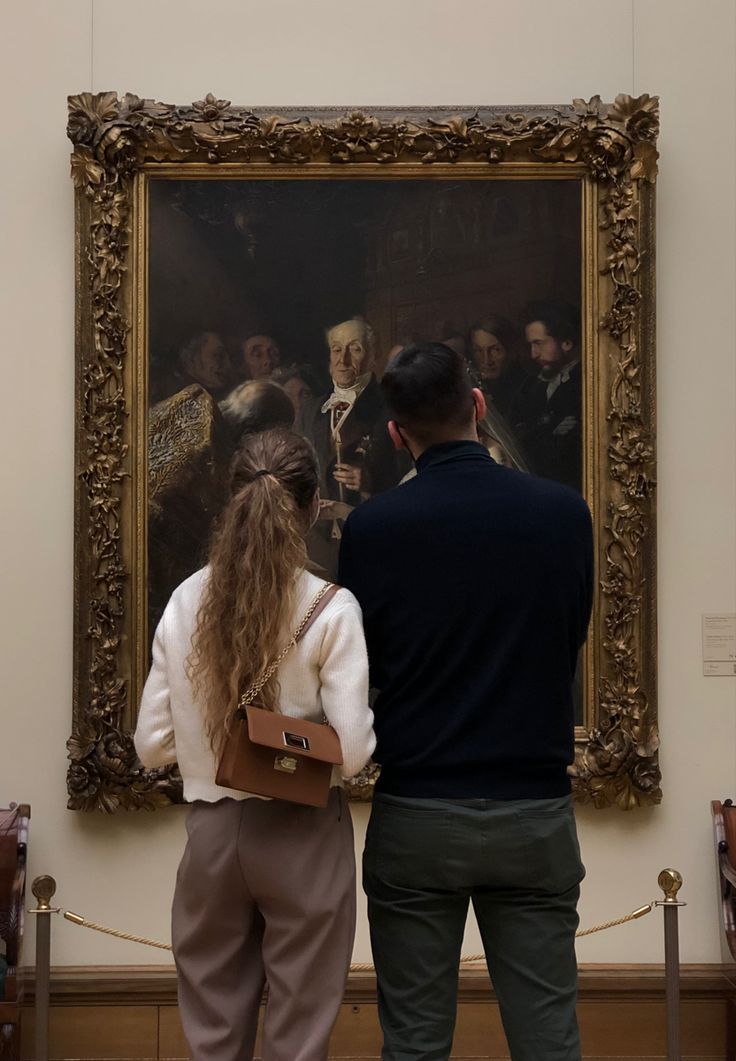 two people standing in front of a painting