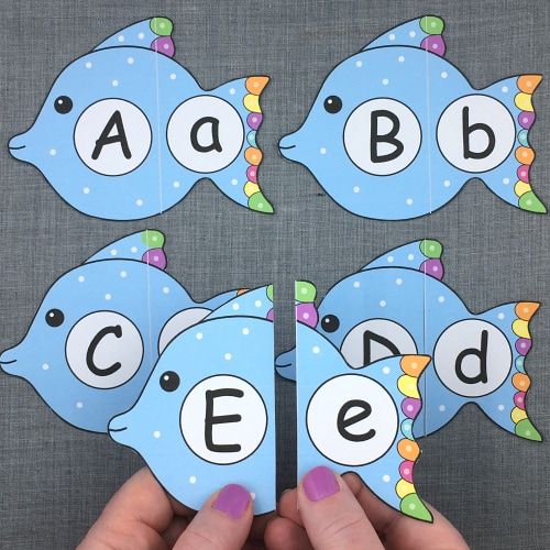 two hands holding up matching cards with letters and fish on them to spell out the word