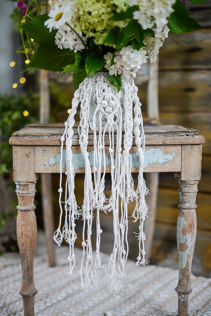 a wooden table with a vase filled with flowers on top of it next to a chair