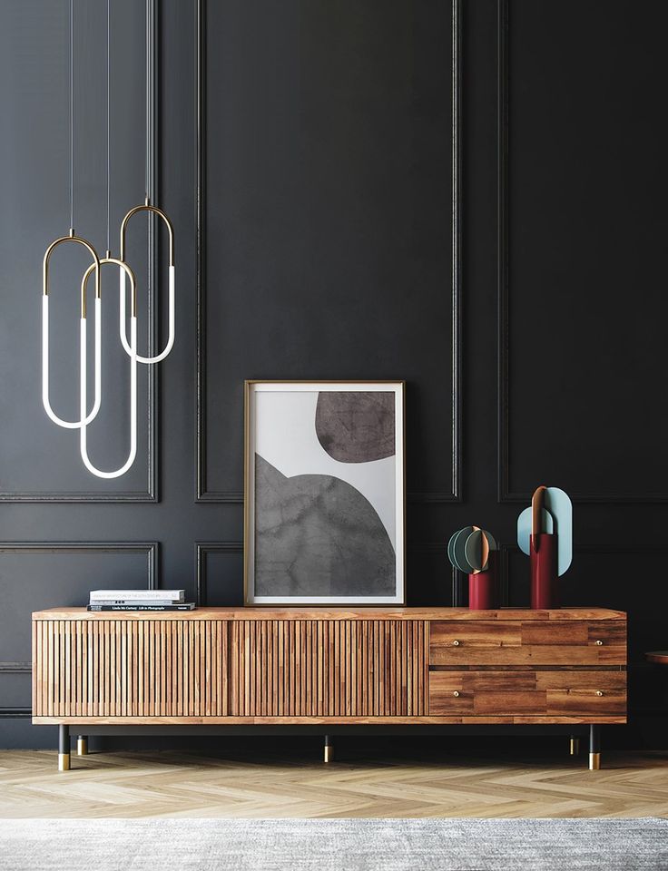 a black wall with some art hanging on it and a wooden cabinet in the foreground