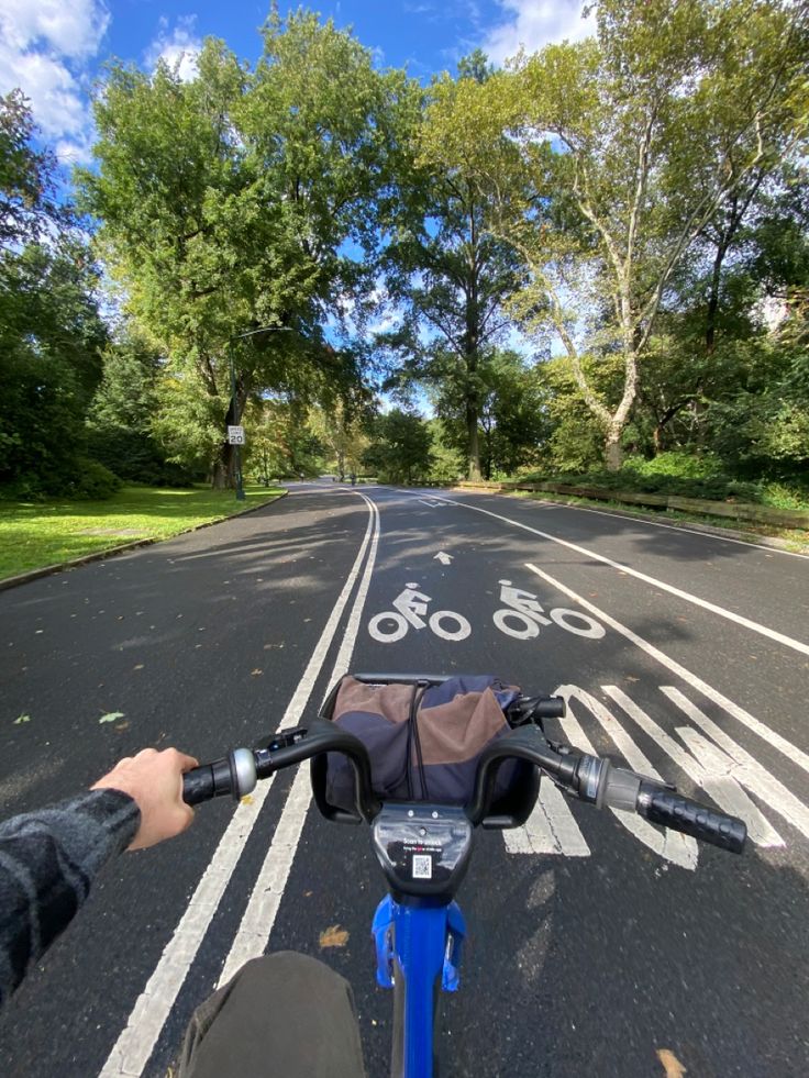 a person riding a bike down a street with trees in the backgroung