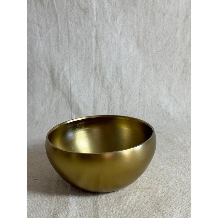 a gold bowl sitting on top of a white sheet