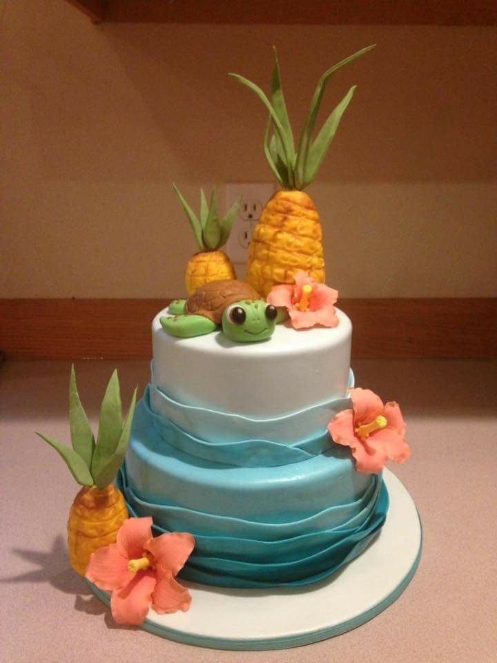 a three tiered cake decorated with pineapples and flowers