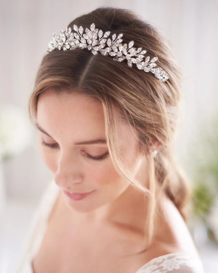 a woman wearing a bridal headpiece with flowers on it's side and her eyes closed