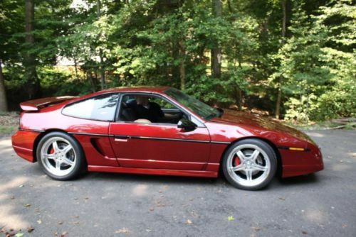 a red sports car parked in front of some trees