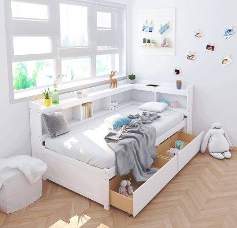 a white bed with drawers underneath it and stuffed animals on the floor next to it