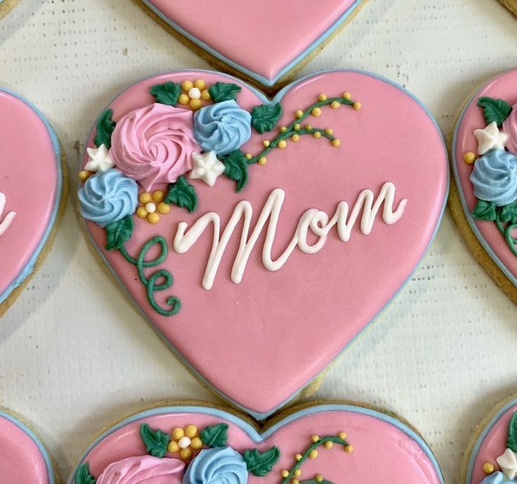 decorated cookies arranged in the shape of heart with mom written on it and flowers around them