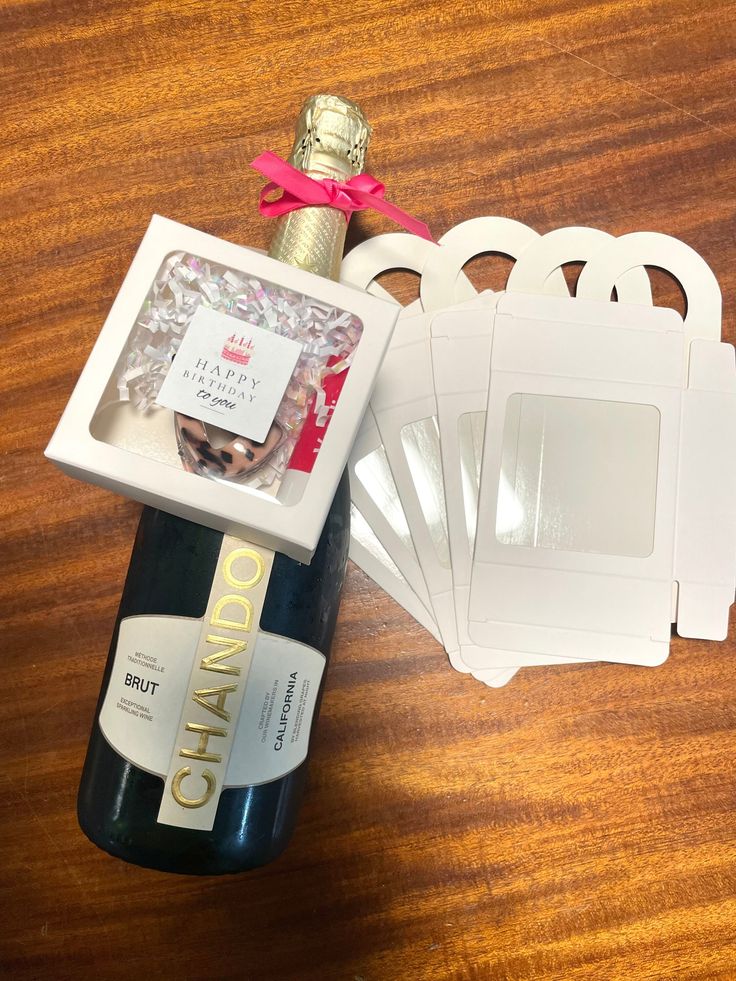 the wine bottle is next to several coasters and a corkscrew with a pink ribbon