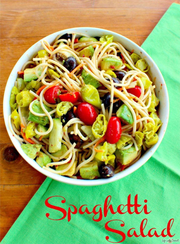 a white bowl filled with pasta salad on top of a green napkin