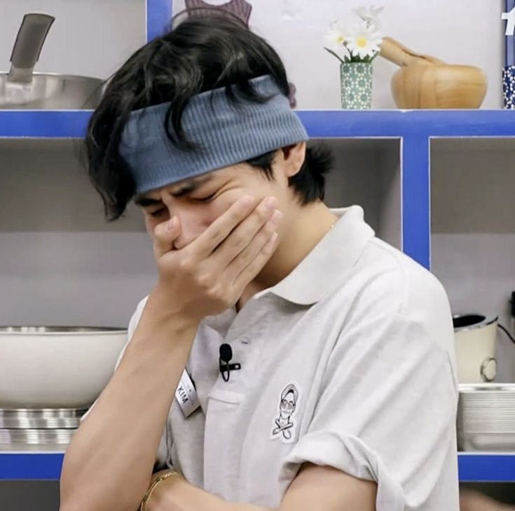 a man with a blindfold covering his face in front of a shelf full of pots and pans