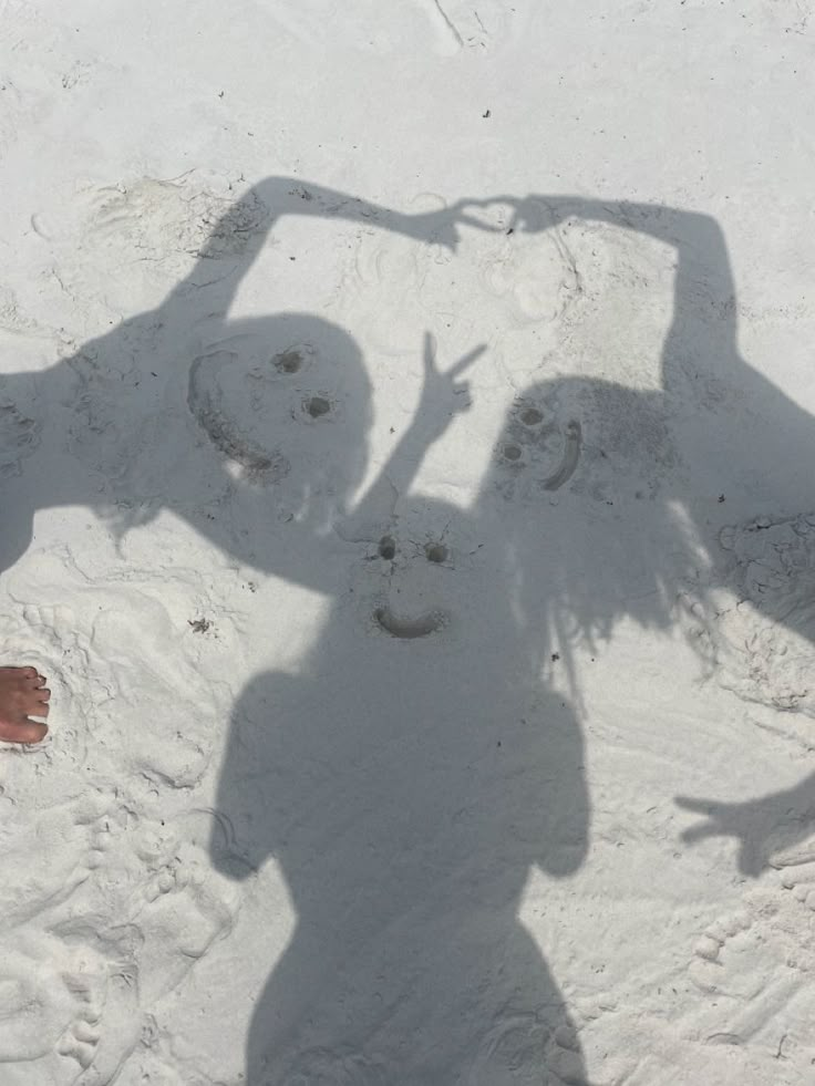 two people are standing in the snow with their shadow on the ground and one person is making a face