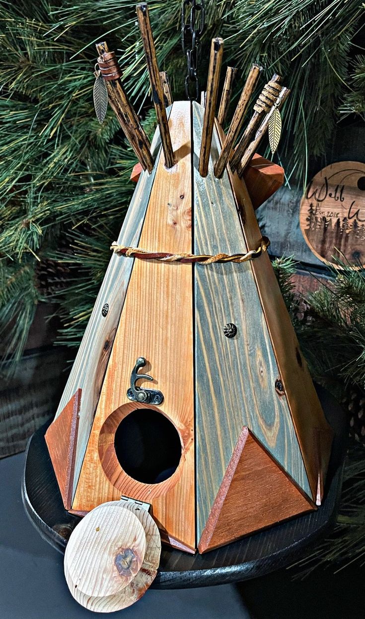 a birdhouse made out of wooden sticks and wood shavings on top of a black plate