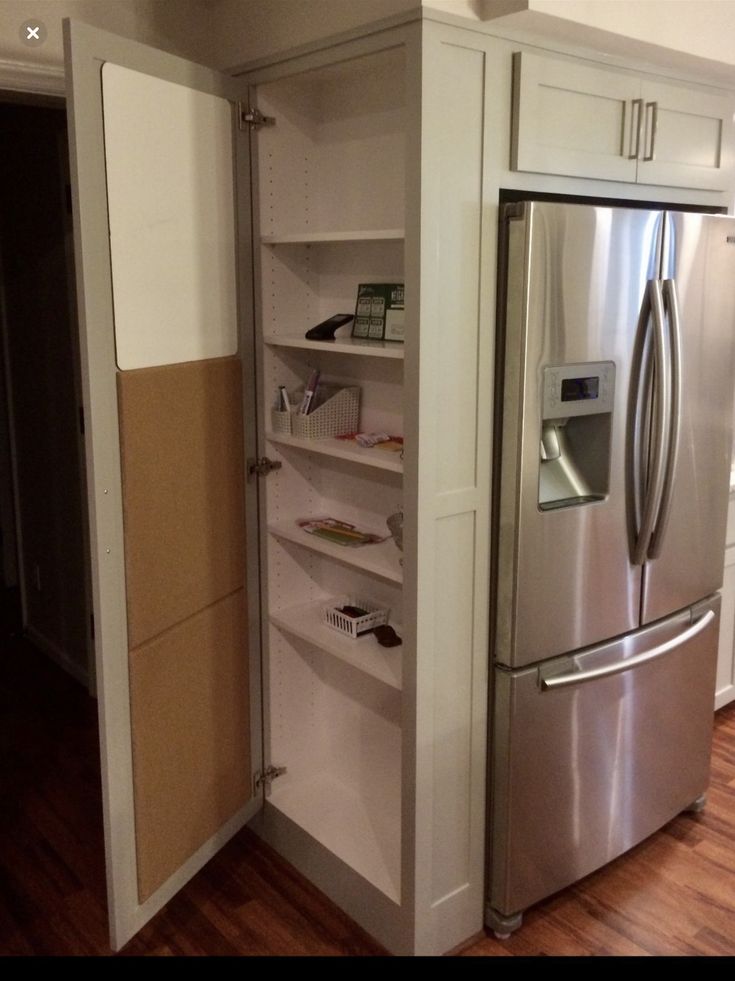 a stainless steel refrigerator and freezer combo in a kitchen with hardwood floors, white cabinets and wood flooring