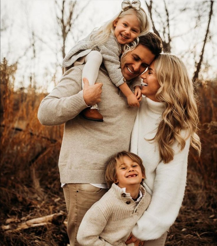 a woman and two children are posing for a family photo in front of some trees