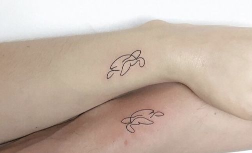 two people with matching tattoos on their arms, one is holding the other's arm