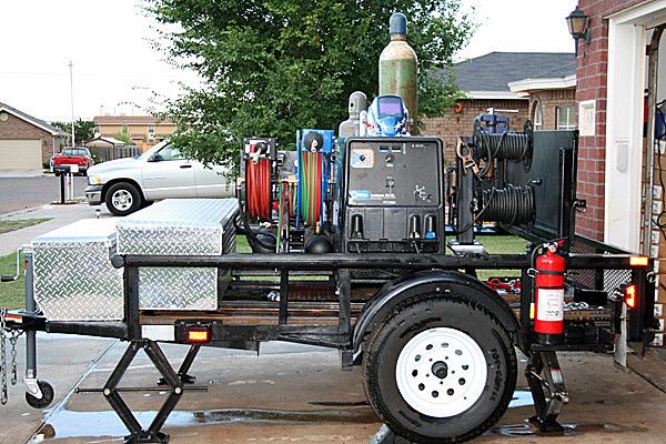 there is a trailer that has various items on it and parked in front of a house