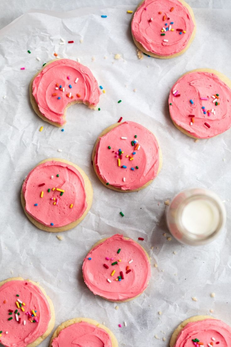 pink frosted cookies with sprinkles and a glass of milk on the side