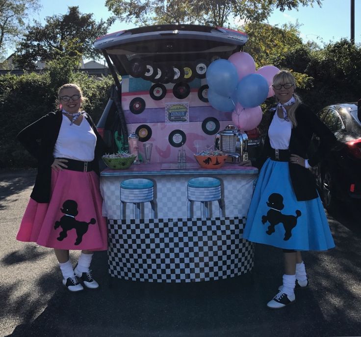 two women in costumes standing next to a food cart