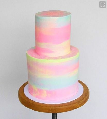 a multi - colored cake on a wooden stand