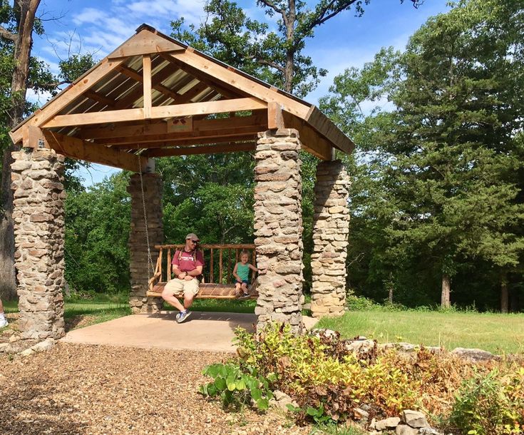 a man sitting on a bench under a wooden gazebo