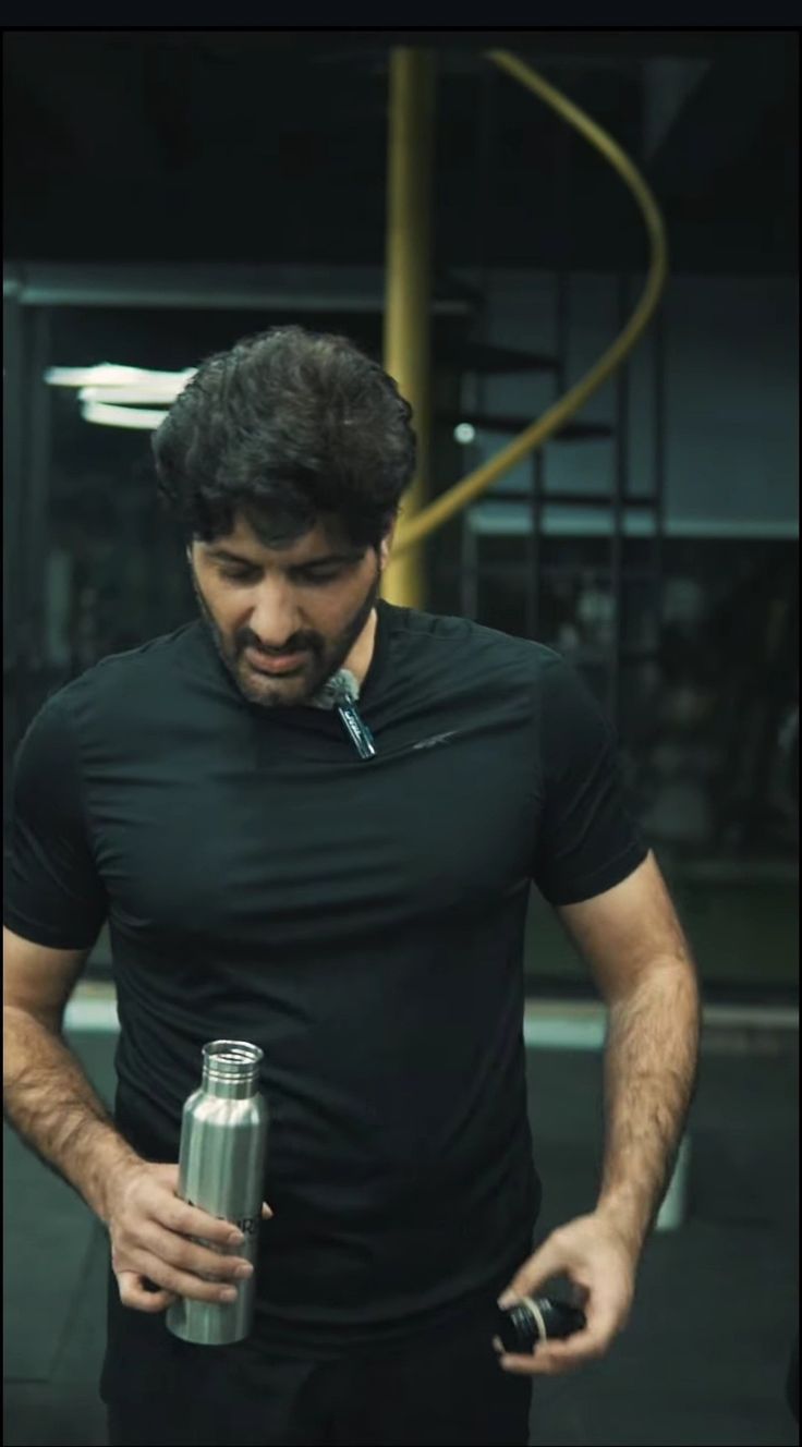 a man in black shirt holding a metal cup