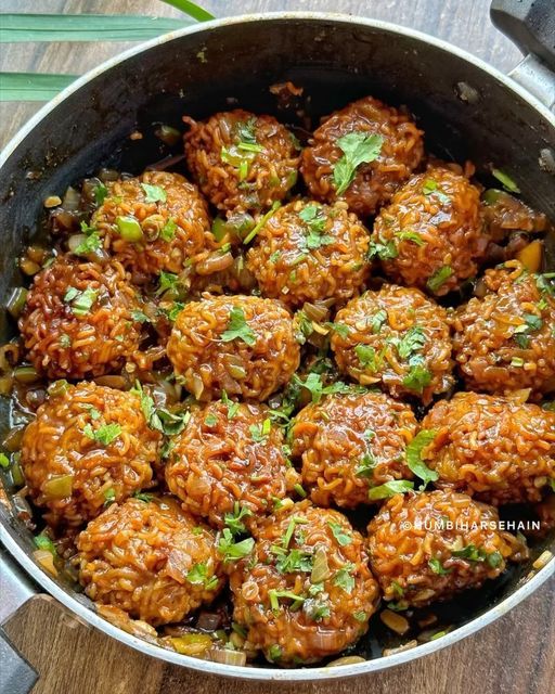 meatballs with herbs in a pan on a wooden counter top next to chopsticks