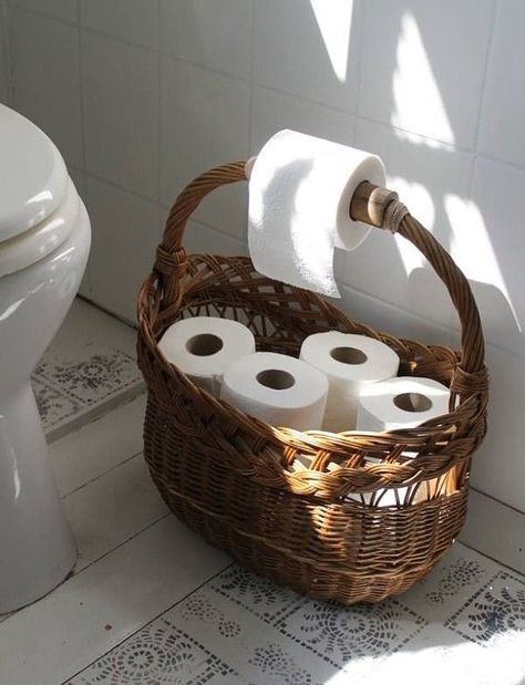 a wicker basket with rolls of toilet paper in it next to a white toilet