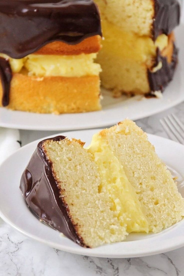 two slices of cake on white plates with chocolate frosting and one slice has been cut