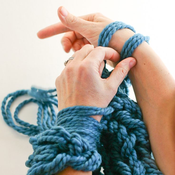 the woman is knitting her blue hand knitted armwars with two hands together