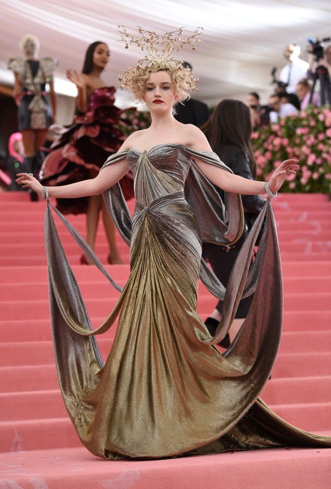 a model walks down the runway in a gold gown