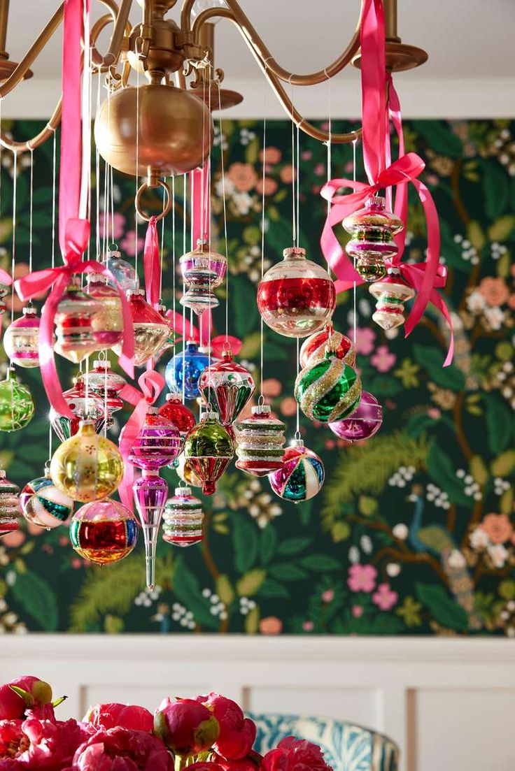 a chandelier filled with ornaments hanging from it's sides in front of a floral wallpaper