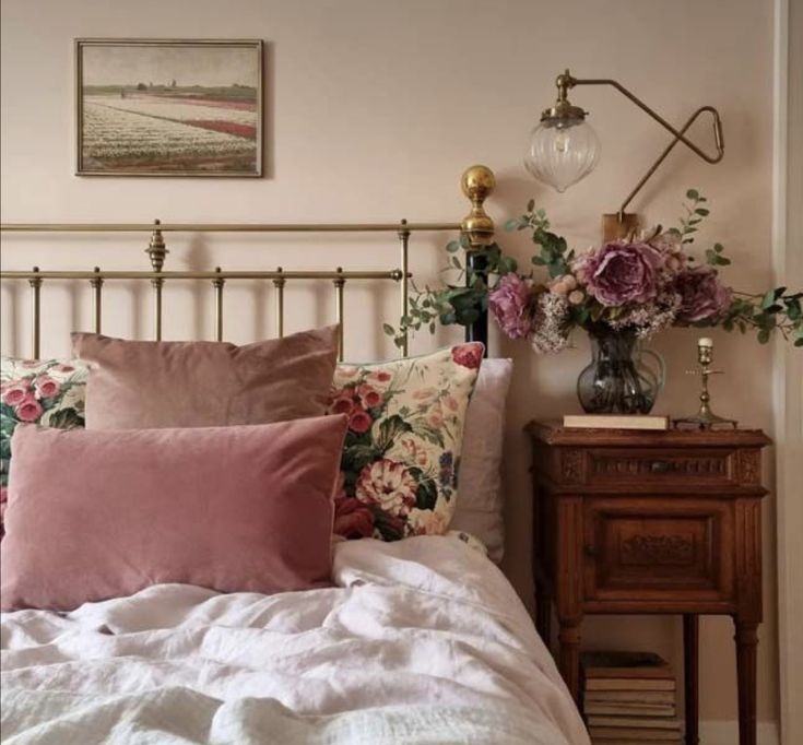 a bed with pink and white flowers on the headboard next to a night stand