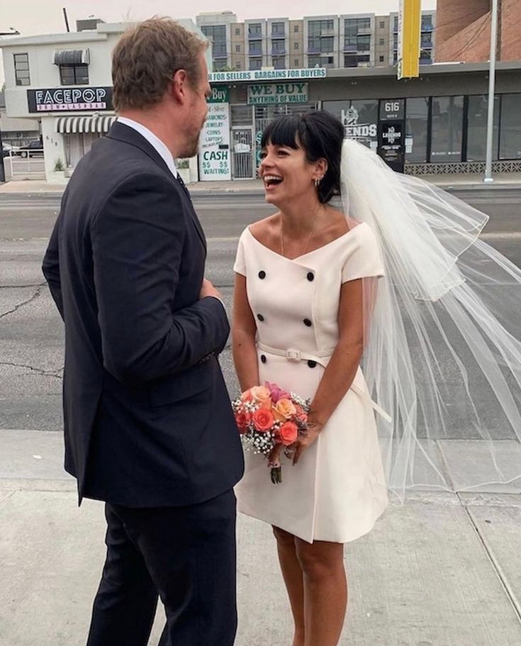 a man in a suit and tie standing next to a woman wearing a wedding dress