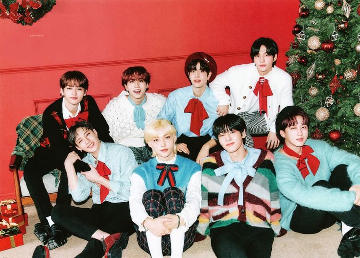 a group of young men sitting next to each other in front of a christmas tree