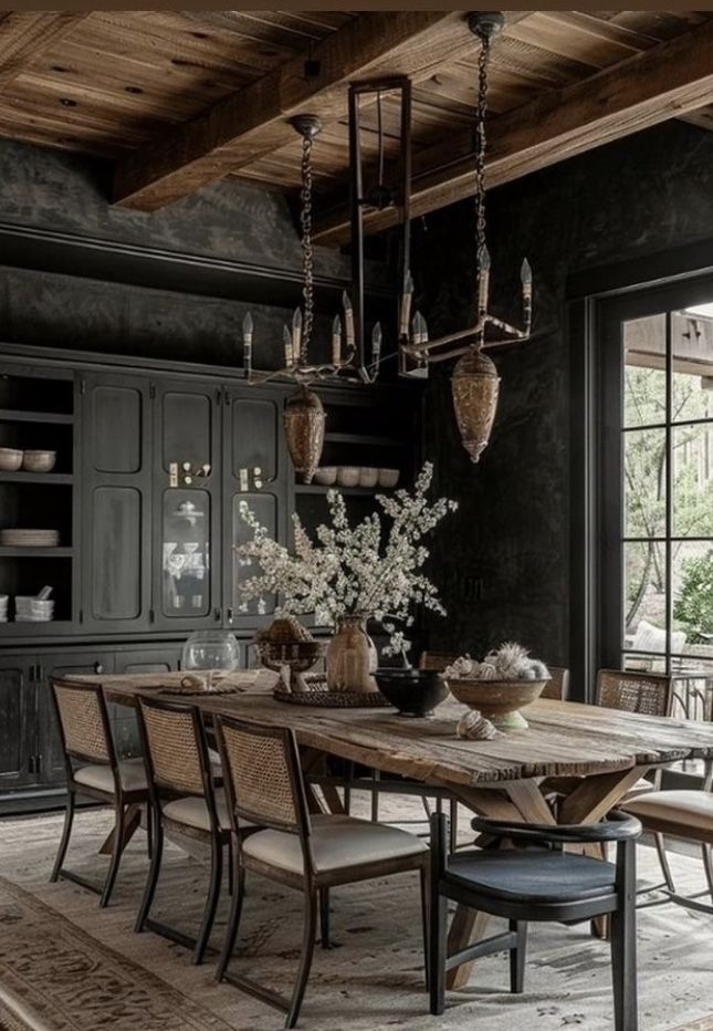 an elegant dining room with black walls and wooden floors, chandelier above the table