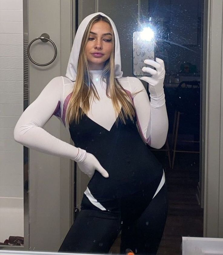 a pregnant woman taking a selfie in front of a mirror with her cell phone