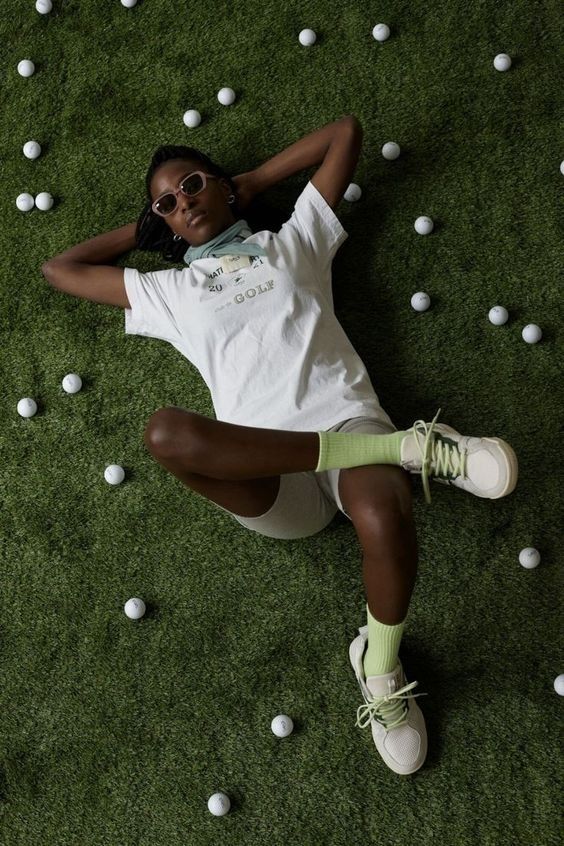 a woman laying on the ground surrounded by white balls and wearing sunglasses, with her arms behind her head