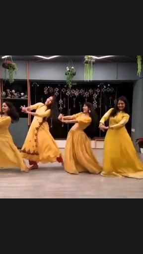 four women in yellow dresses are dancing on the dance floor with their arms outstretched and legs spread out