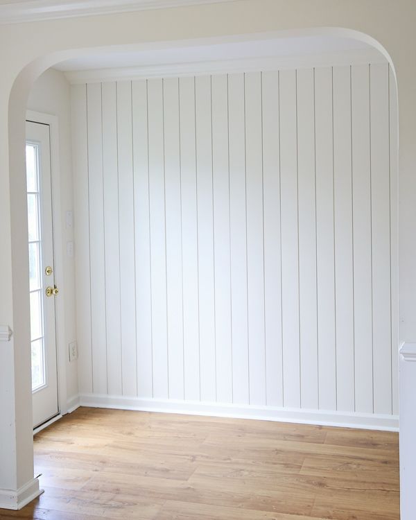 an empty room with white walls and wood floors