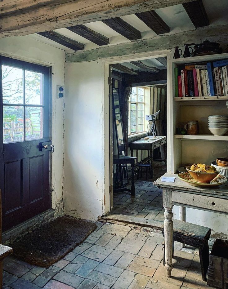 a room with a table, bookshelf and door to another room in it