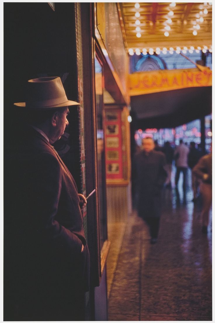 a man in a hat looking at his cell phone while standing next to an elevator