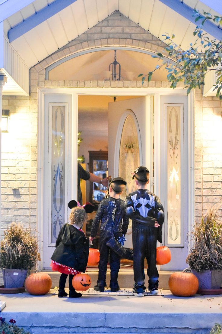 three children dressed up as mickey and minnie mouse in front of a house with pumpkins