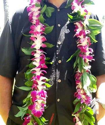 a man wearing a lei with pink flowers on it's neck and black shirt