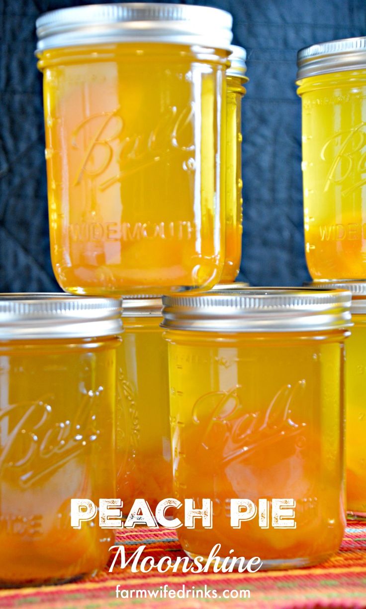 four jars filled with yellow liquid sitting on top of a table