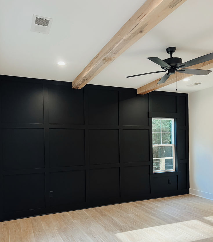 an empty room with black walls and ceiling fan