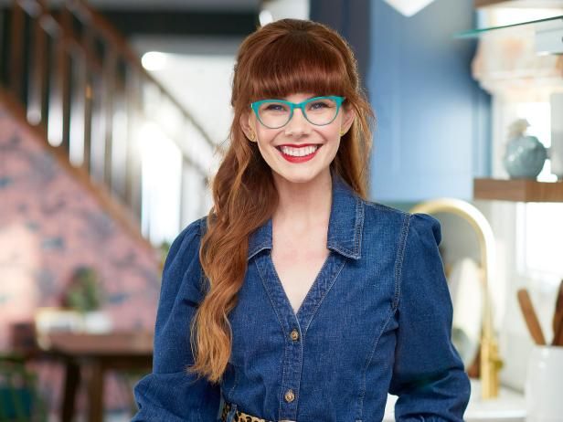 a woman wearing glasses standing in a kitchen